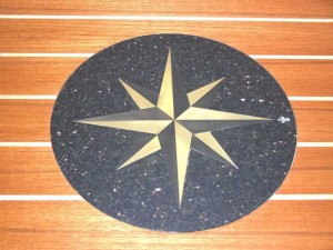 12 diameter compass rose medallion for bar top at a private yacht club. Circle is 1/2 thick black granite, compass points are from 1/8 thick polished brass and patinated brass. Fleur-di-lis is from 1/4 thick stainless steel. Waterjet Carving